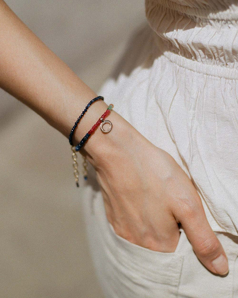 sapphires, emeralds and rubies beaded bracelet handstrung on silk thread handcrafted in London with 9ct solid gold organic charm by Maya Magal London