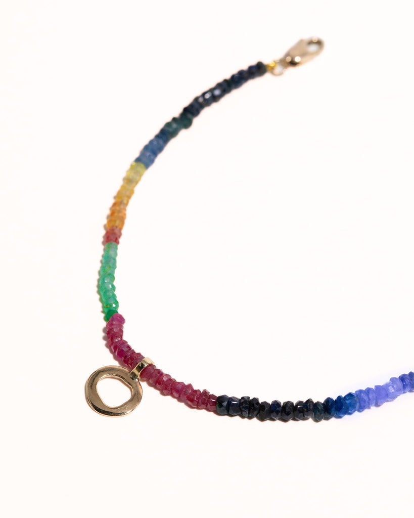 sapphires, emeralds and rubies beaded bracelet handstrung on silk thread handcrafted in London with 9ct solid gold organic charm by Maya Magal London