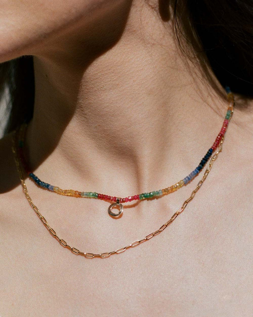 sapphires, emeralds and rubies beaded necklace handstrung on silk thread handcrafted in London with 9ct solid gold organic charm by Maya Magal London